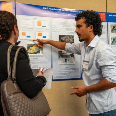 Student pointing at their conference poster